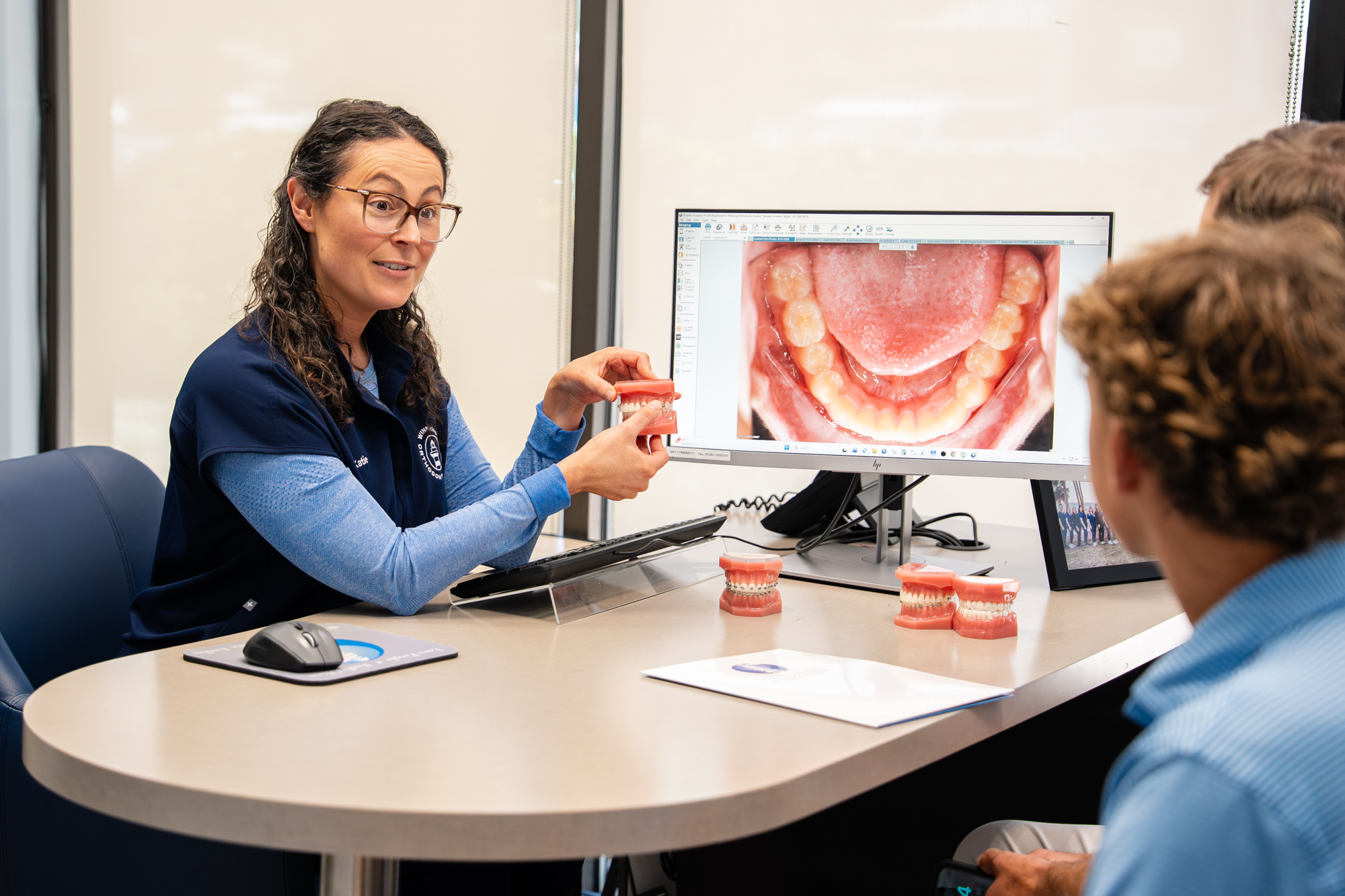 Treatment coordinator reviewing a digital smile scan and aligner models with a patient