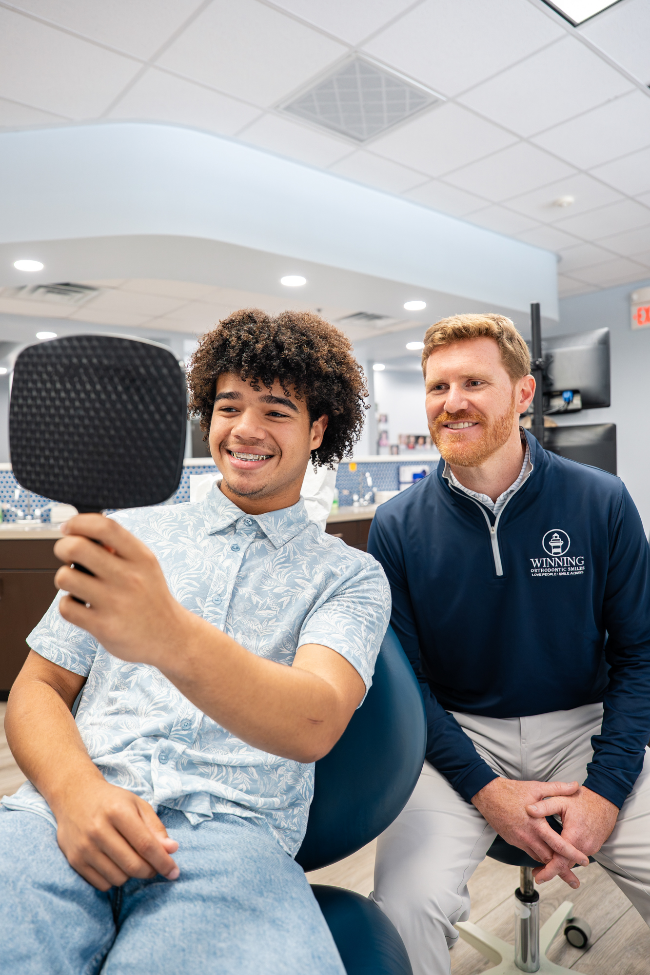 Patient checking his new smile in a hand mirror with his orthodontist at the Walterboro office