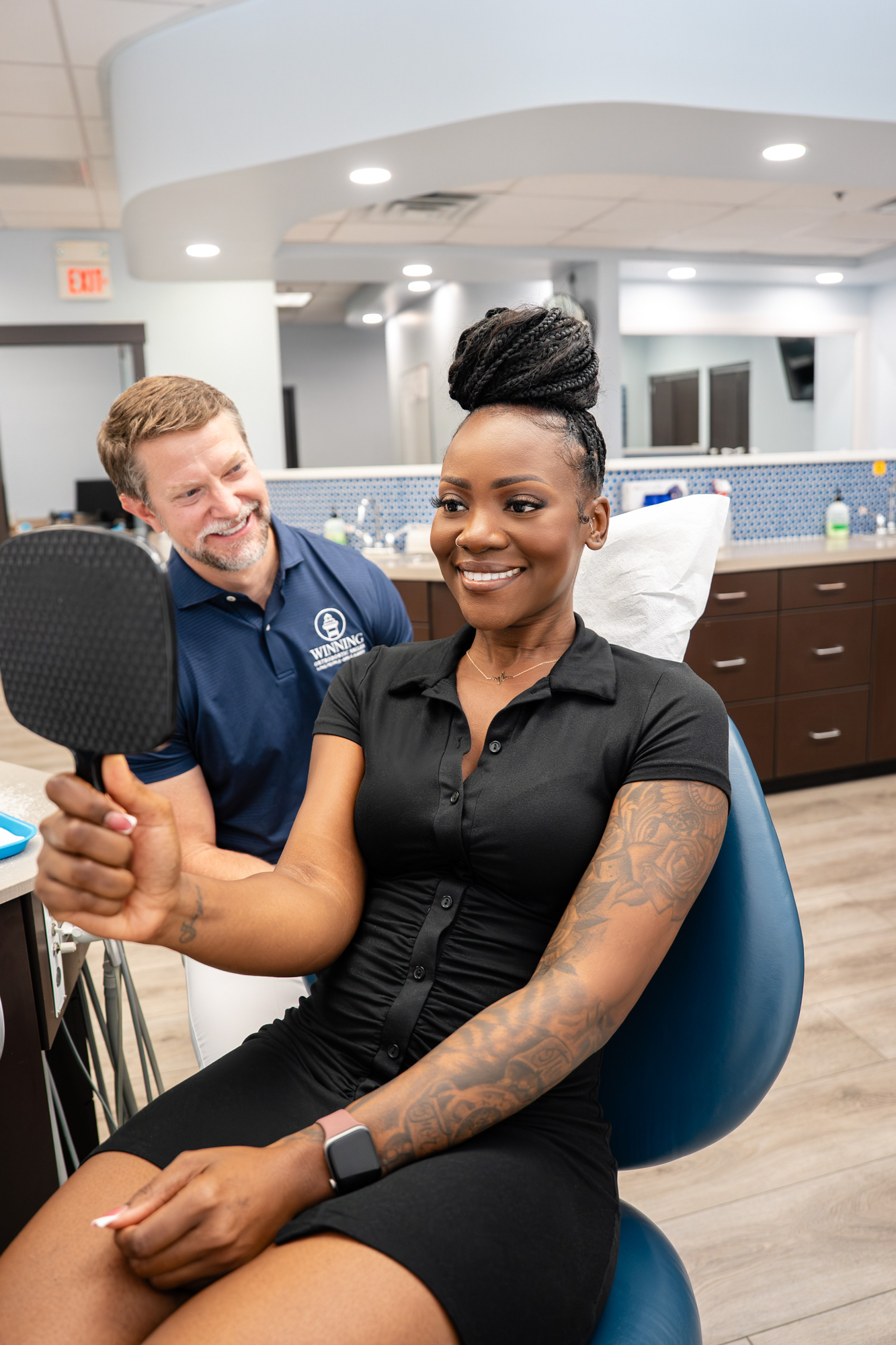 Patient seeing her new smile in the mirror with the orthodontist beside her